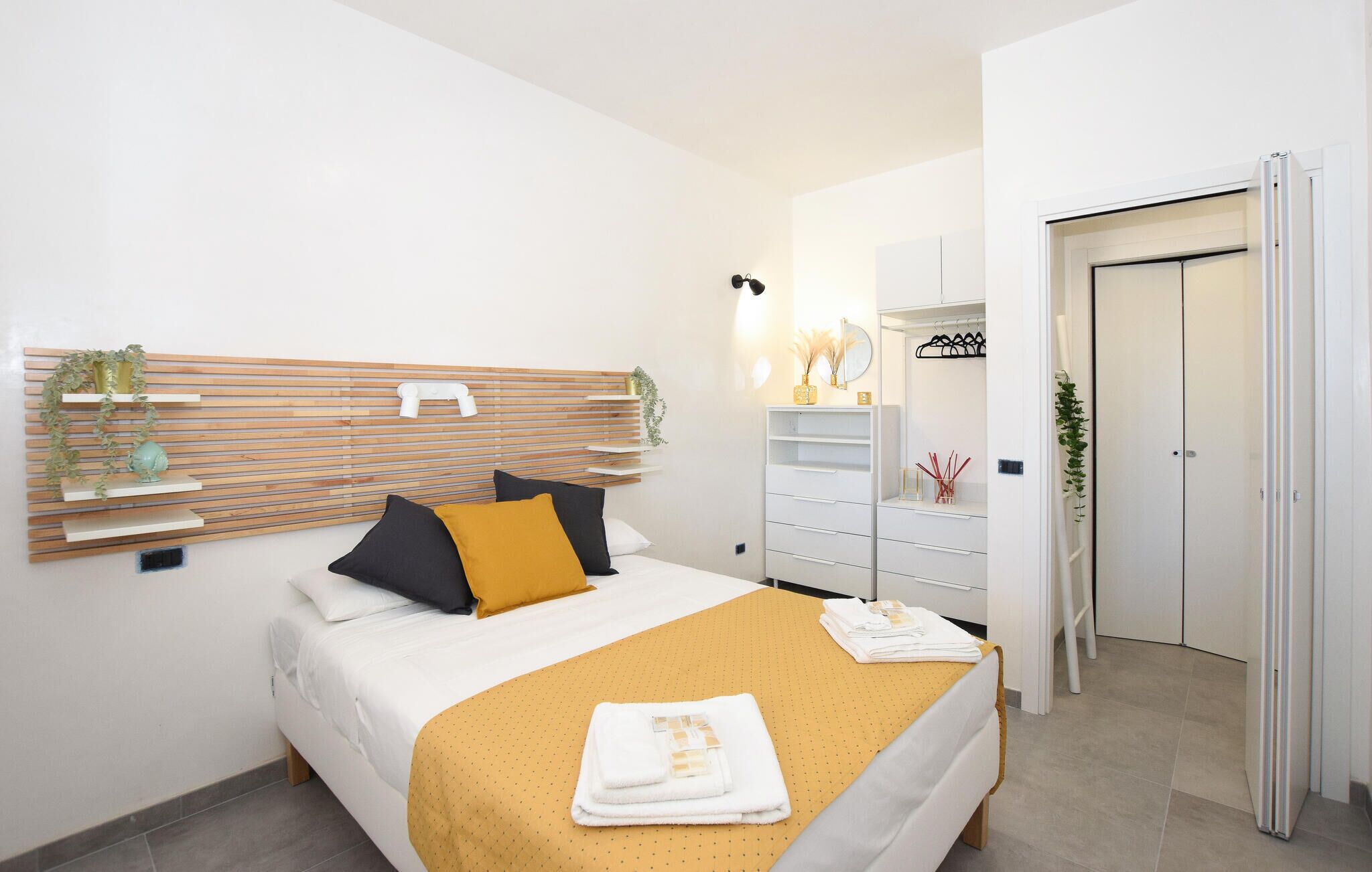 A modern bedroom with a bed, bedside tables, a wardrobe, and a mirror.