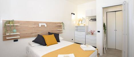 A modern bedroom with a bed, bedside tables, a wardrobe, and a mirror.