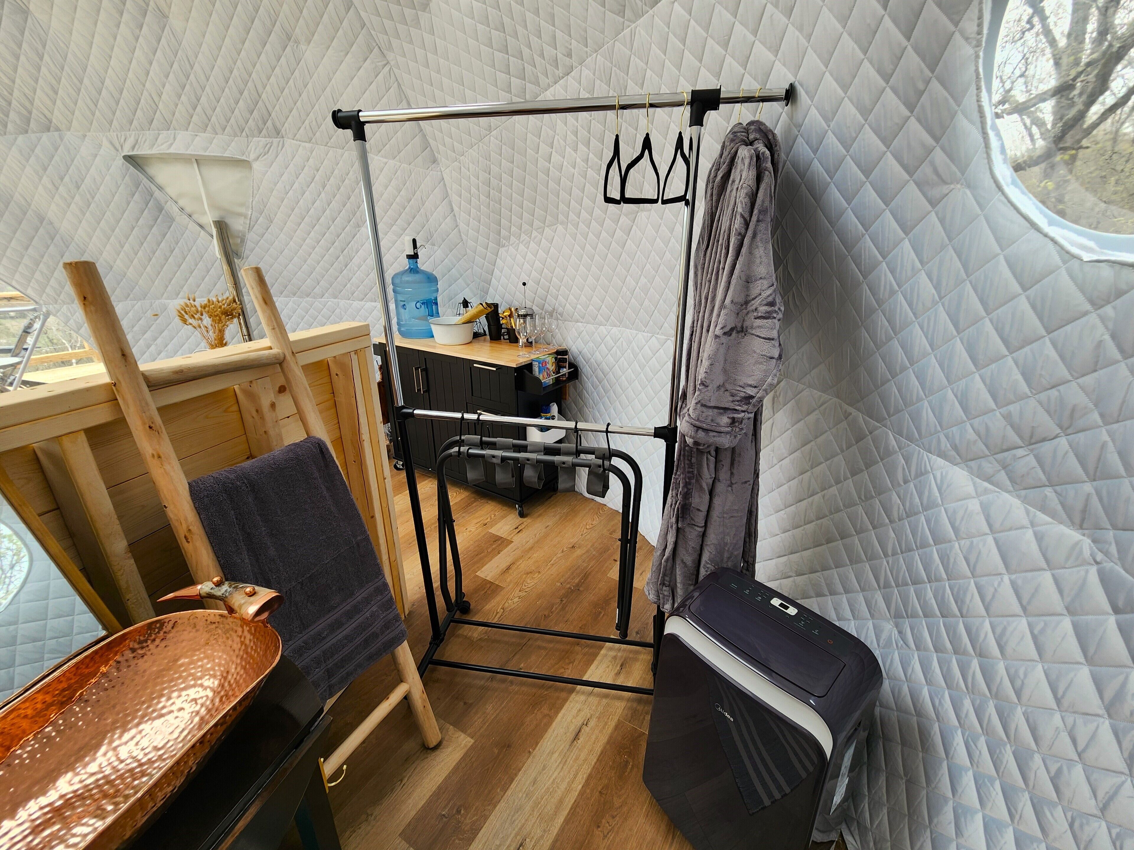 A compact room with a bed, a small table, a water dispenser, and a window.