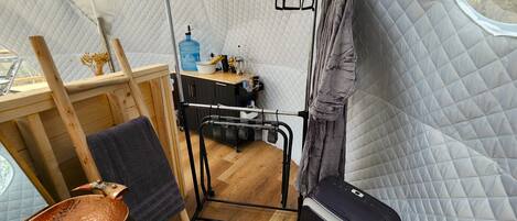A compact room with a bed, a small table, a water dispenser, and a window.