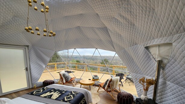 A cozy, tent-like room with a bed, seating area, and a view of the outdoors. - RIVER VIEW Cliff Dome Glamping @ White River, minutes to fishing, hikes! (Cotter)