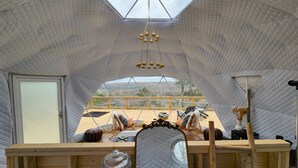 A cozy, tent-like interior with a wooden table, a hanging light fixture, and a view of the outdoors. - RIVER VIEW Cliff Dome Glamping @ White River, minutes to fishing, hikes! (Cotter)