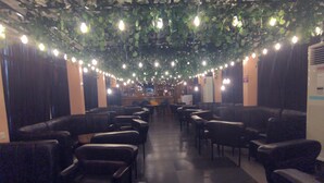 A restaurant with booths and tables, string lights, and a ceiling with hanging plants. - SMILE-T CONTINENTAL HOTEL (Lagos)