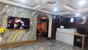 A lobby with a marble floor, a reception desk, a TV mounted on the wall, and a staircase leading to another area. - SMILE-T CONTINENTAL HOTEL (Lagos)