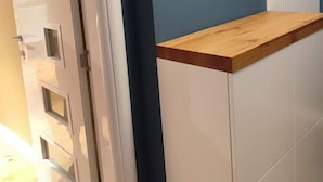 Une pièce avec un plancher en bois, une armoire blanche avec un dessus en bois et un mur bleu.