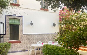A patio area with a white tiled wall, two wall-mounted lights, and a small table with chairs. - Gorgeous home in Malaga (Malaga)