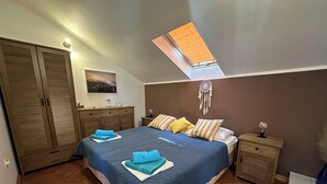 Une chambre à coucher avec un grand lit, une armoire, une table de chevet et une lampe de chevet, ainsi qu’un luminaire au plafond.