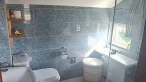 Une salle de bain comprenant des toilettes, un lavabo et un espace douche.
