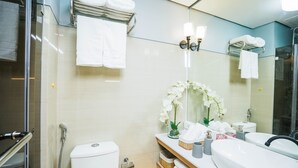 Une salle de bain moderne dotée d’une douche à parois de verre, de toilettes, d’un meuble-lavabo avec un évier et un miroir, et d’un porte-serviettes avec des serviettes pliées.