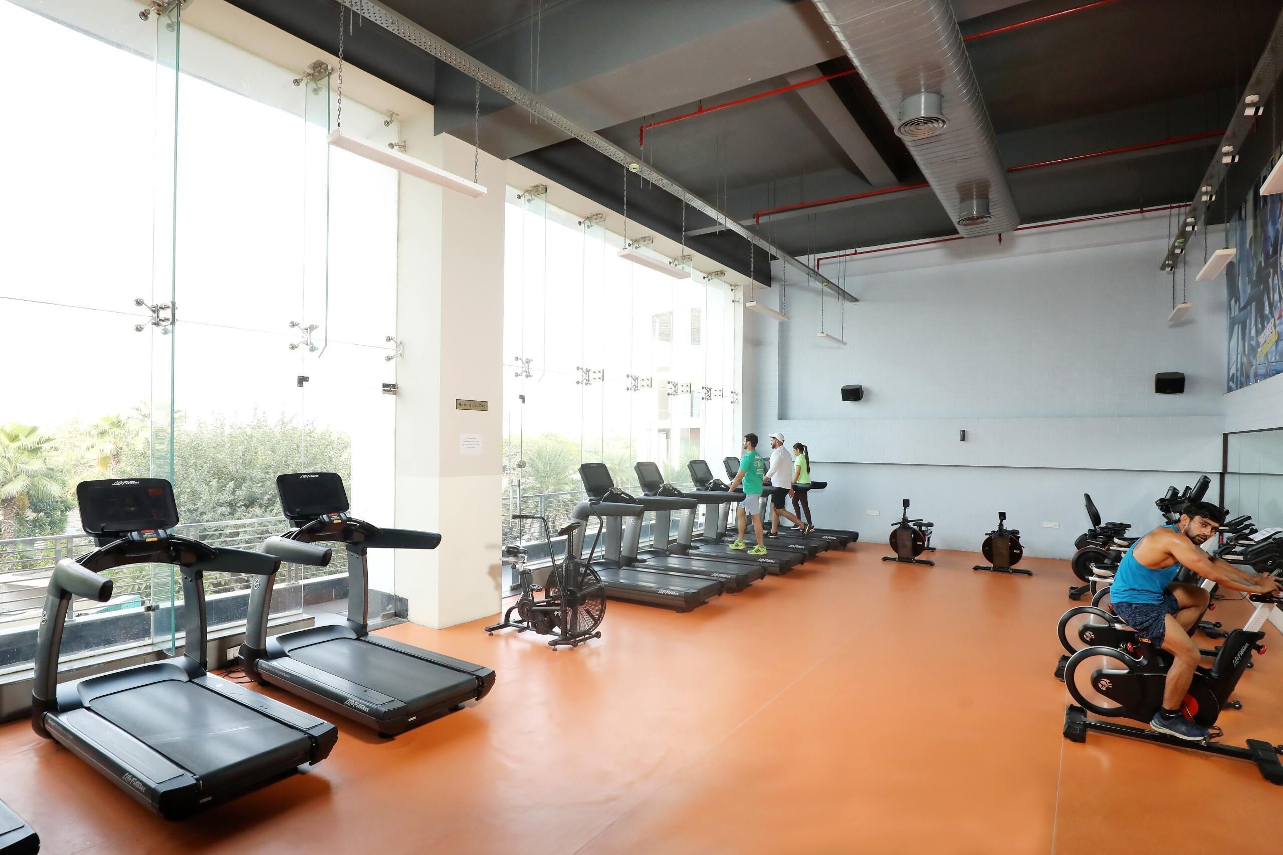 A gym with treadmills, stationary bikes, and a large window.
