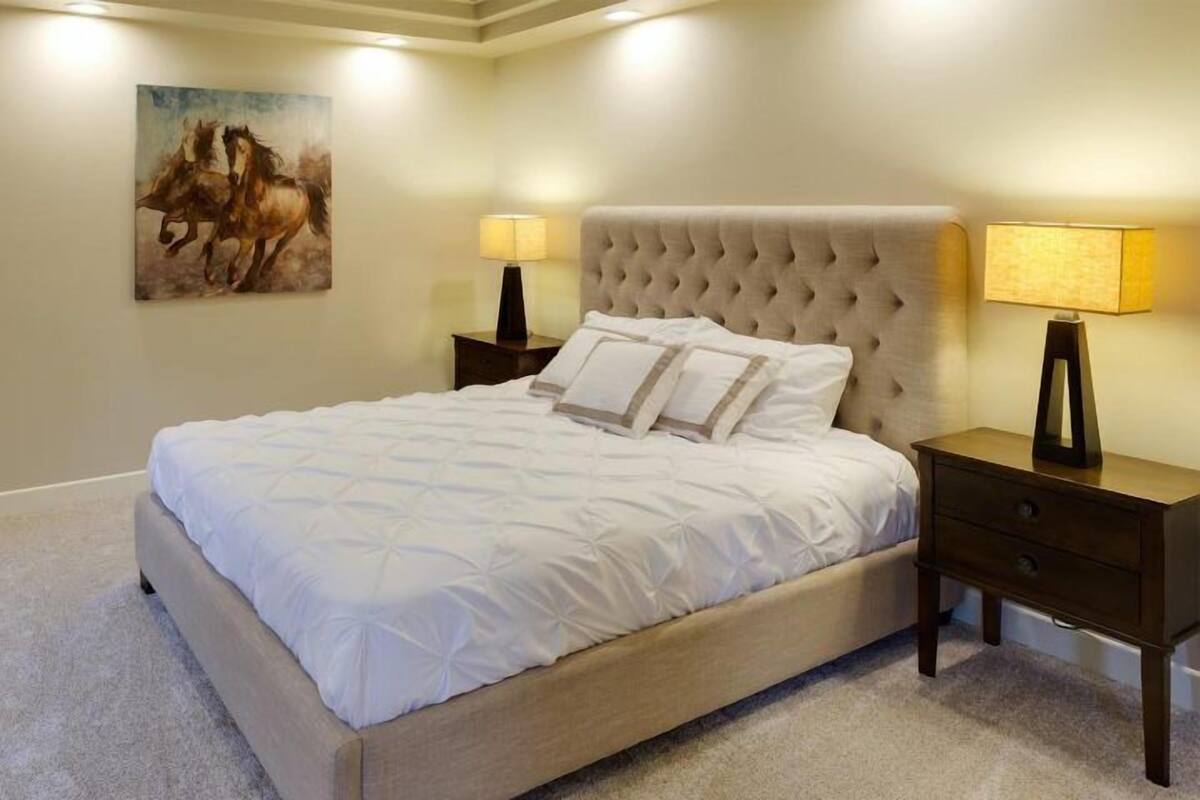 Un dormitorio con una cama grande, dos mesitas de noche y un cuadro en la pared.
