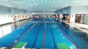 Una piscina con carriles de natación, bloques de salida y una silla de salvavidas.