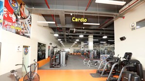 Un gimnasio con equipo cardiovascular, máquinas de pesas y un letrero que indica el área de cardio.