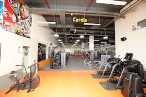 Un gimnasio con equipo cardiovascular, máquinas de pesas y un letrero que indica el área de cardio.