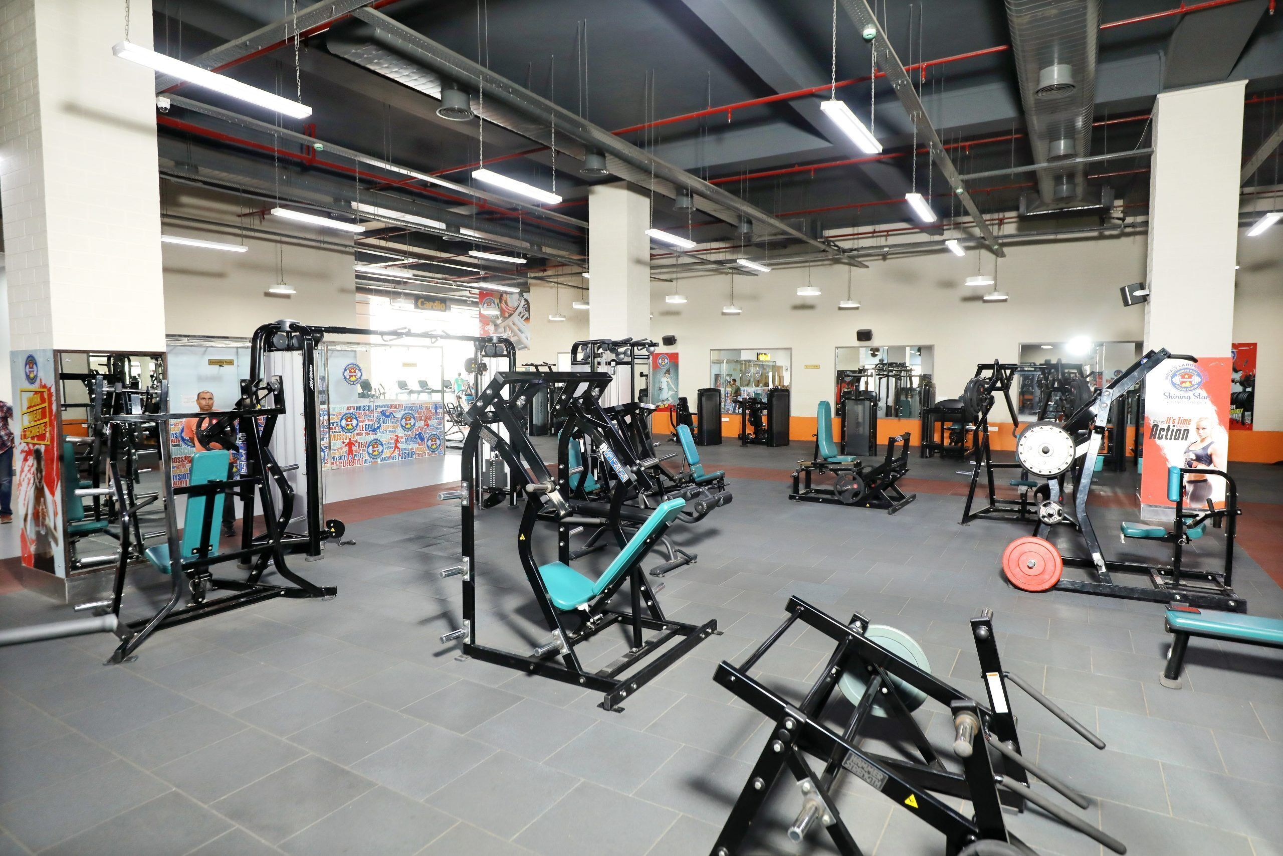 Una palestra con diverse macchine per esercizi, tra cui panche pesi e rastrelliere per lo squat.