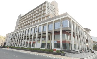 Un edificio de varios pisos con un diseño arquitectónico moderno, que presenta una serie de balcones y grandes ventanales.