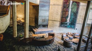 A modern interior with a fireplace, seating area, and large windows overlooking a natural scene. - Snowbird's PREMIER Ski-in Ski-out Suite @ Iron Blosam Lodge (Snowbird)
