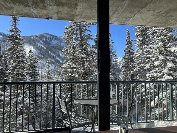 A balcony with a view of snow-covered trees and mountains.