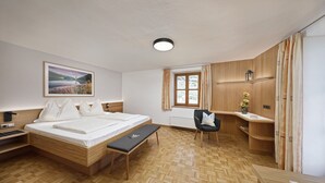 Una habitación de hotel moderna con una cama de madera, un escritorio, una silla y un ventanal con cortinas.