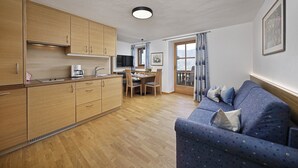 Una cocina moderna con armarios de madera, una zona de comedor con mesa y sillas, y un sofá azul con cojines.