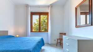 Un dormitorio con cama, cómoda, silla y ventana con cortinas.