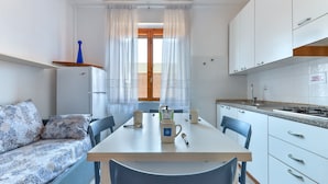 Una cocina funcional con mesa, sillas, sofá y ventana con cortinas.