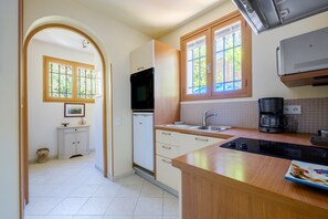 A kitchen with a stove, sink, and window. - Apartment 'Grand Studio Bougainvillée' with Shared Pool, Private Terrace and Wi-Fi (Cagnes-sur-Mer)