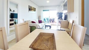 Una sala de estar moderna con una mesa de comedor de madera, un sofá y un televisor.