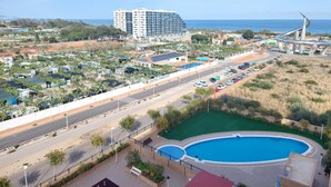 Un resort con piscina, una carretera y un edificio grande al fondo.