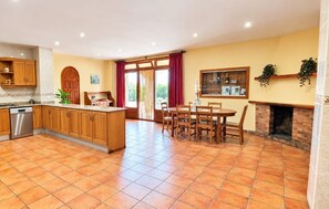 A spacious kitchen with a dining area, a built-in oven, and a large window with curtains. - Country House 'Les Cabretes Vilanova De La Muga' with Mountain View, Wi-Fi and Air Conditioning (Vilanova De La Muga)