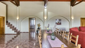 Un vaste espace dédié à la salle à manger, avec une longue table en bois, des chaises et un canapé rouge.
