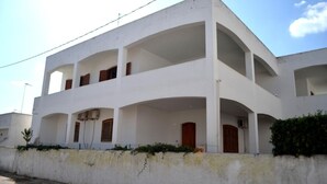 Un edificio de varios pisos con balcones, fachada blanca y techo plano.