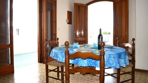 Un comedor con una mesa redonda, sillas y un mantel azul.