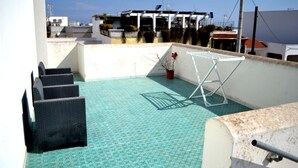 Una terraza en la azotea con suelo estampado, un tendedero y una planta en maceta.
