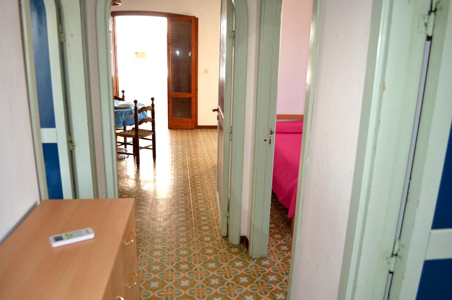 Un couloir étroit doté d’un sol carrelé, de portes en bois et d’une table sur laquelle est posée une nappe.