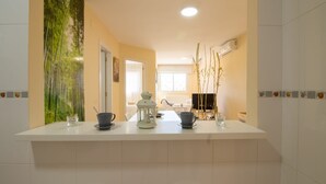 Una cocina con encimera blanca, un refrigerador y un ventanal.