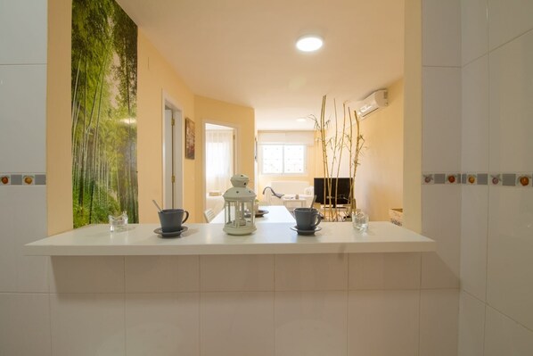 A kitchen with a white countertop, a refrigerator, and a window.
