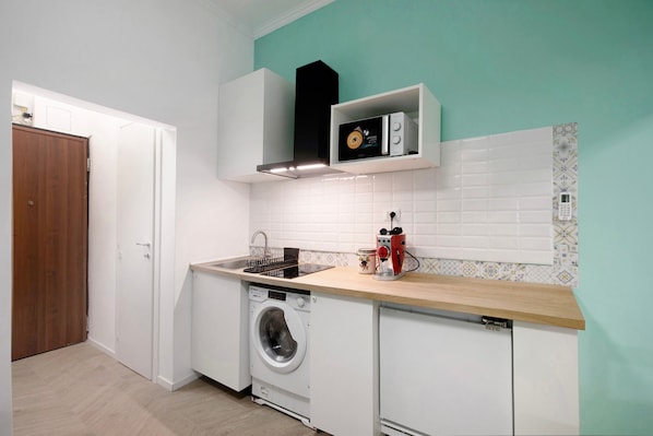 A compact kitchen with a washing machine, a microwave, and a sink.