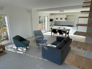 Ein modernes Wohnzimmer mit Sofa, Sessel und Esstisch.