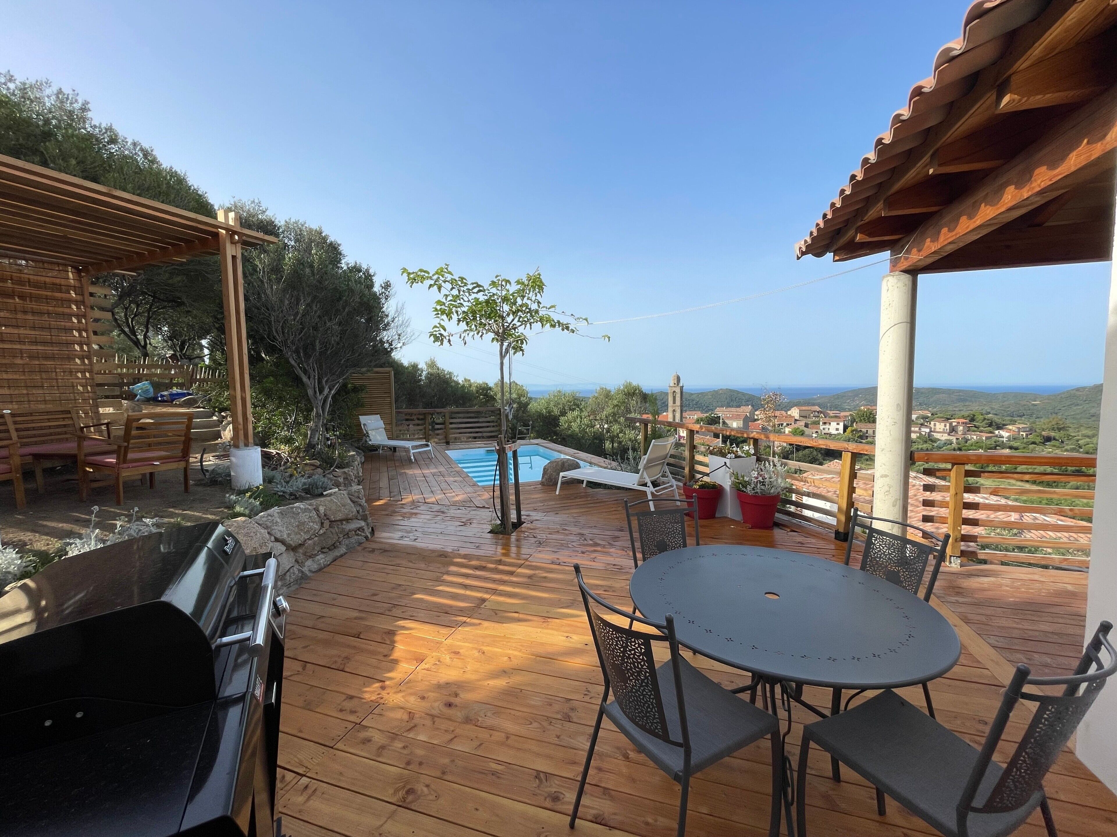 A wooden deck with a pool, outdoor seating, and a view of the landscape.