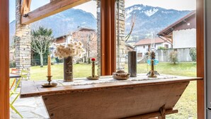 A wooden bench with a view of mountains through large windows. - Chalet 'Pierre Et Bois' with Mountain View, Private Terrace and Wi-Fi (AIGUEBLANCHE)