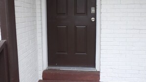 A dark brown door with a white-framed window, a doormat with "WELCOME" written on it, and a white brick wall. - CLOSE TO FT JACKSON, WILLIAMS-BRICE STADIUM, VA HOSP, FAMILY FRIENDLY. SLEEPS 10 (Columbia)