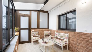 A sunlit balcony with a wooden bench, two chairs, and a small table. - Apartment 'Casa El Isleño' with Sea View, Private Terrace and Wi-Fi (Villa de Valverde)