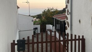 A narrow alleyway with a gated entrance, a small outdoor seating area, and a view of a distant landscape. - Apartment 'Casa El Isleño' with Sea View, Private Terrace and Wi-Fi (Villa de Valverde)