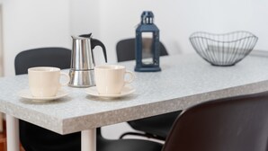 A table with two white cups and saucers, a silver coffee pot, a blue lantern, and a wire basket. - Apartment 'Casa El Isleño' with Sea View, Private Terrace and Wi-Fi (Villa de Valverde)