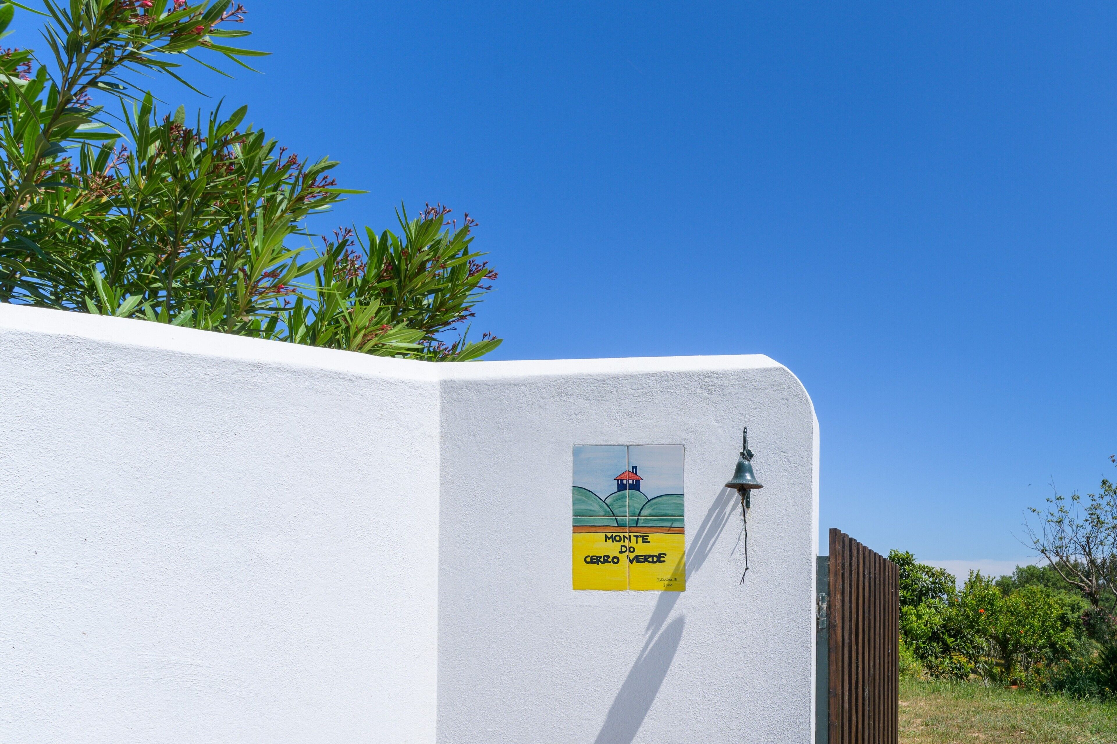 Een witte muur met een bord waarop 'Monte do Cerro Verde' staat.