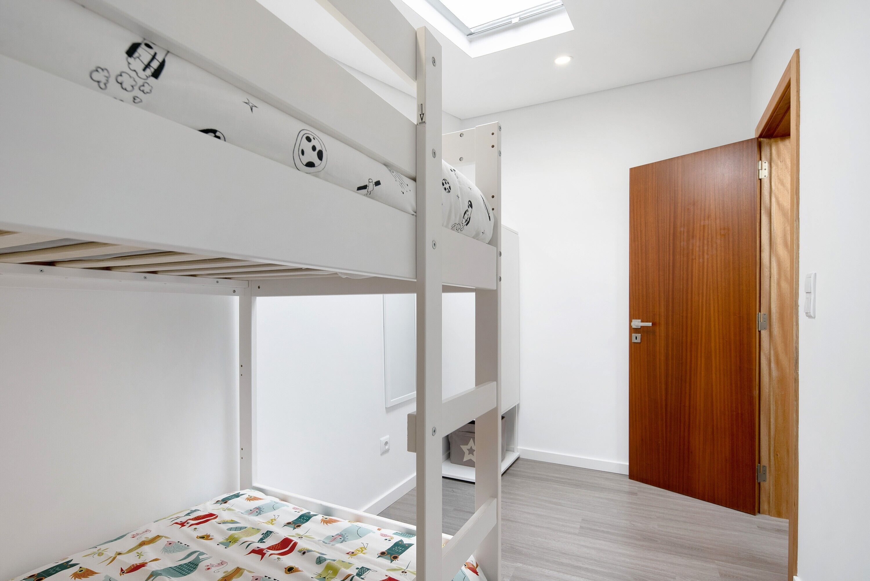 A bunk bed with a pull-up ladder, a wooden door, and a skylight.