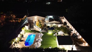 Una propietat residencial amb piscina, mobiliari d'exterior i diversos cotxes aparcats a l'exterior.