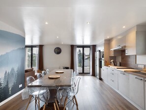Eine moderne Küche mit Essbereich, Holzboden und Blick durch die Glastür.