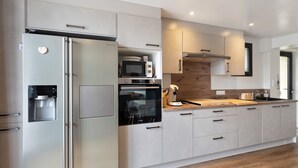 Una cocina moderna con electrodomésticos de acero inoxidable, encimeras de madera y armarios de colores claros.